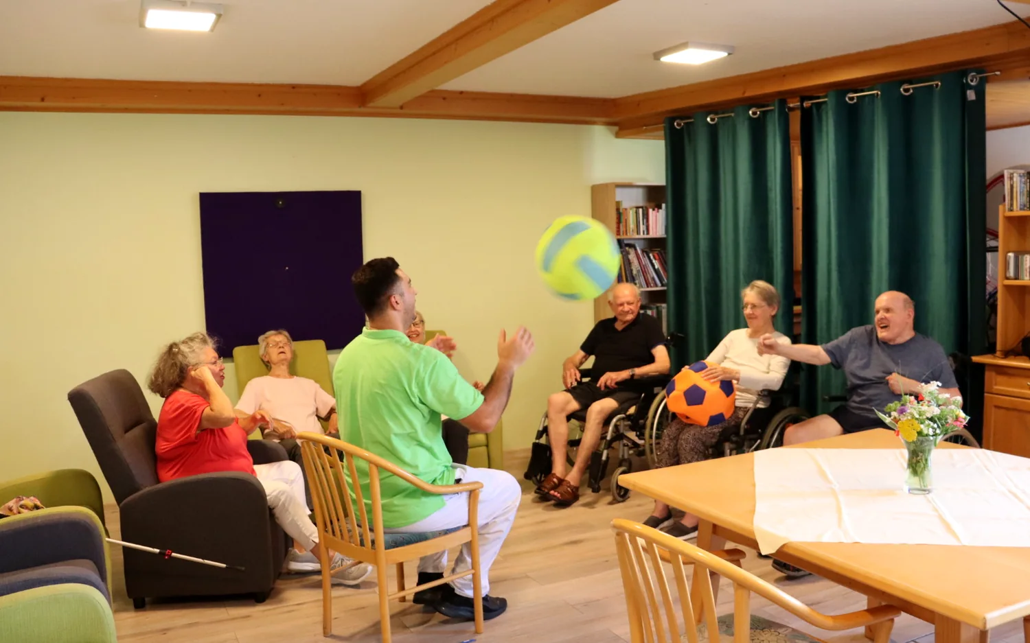 Aktivierungsangebot mit Ballspiel im Aufenthaltsraum des Seniorenpflegeheims