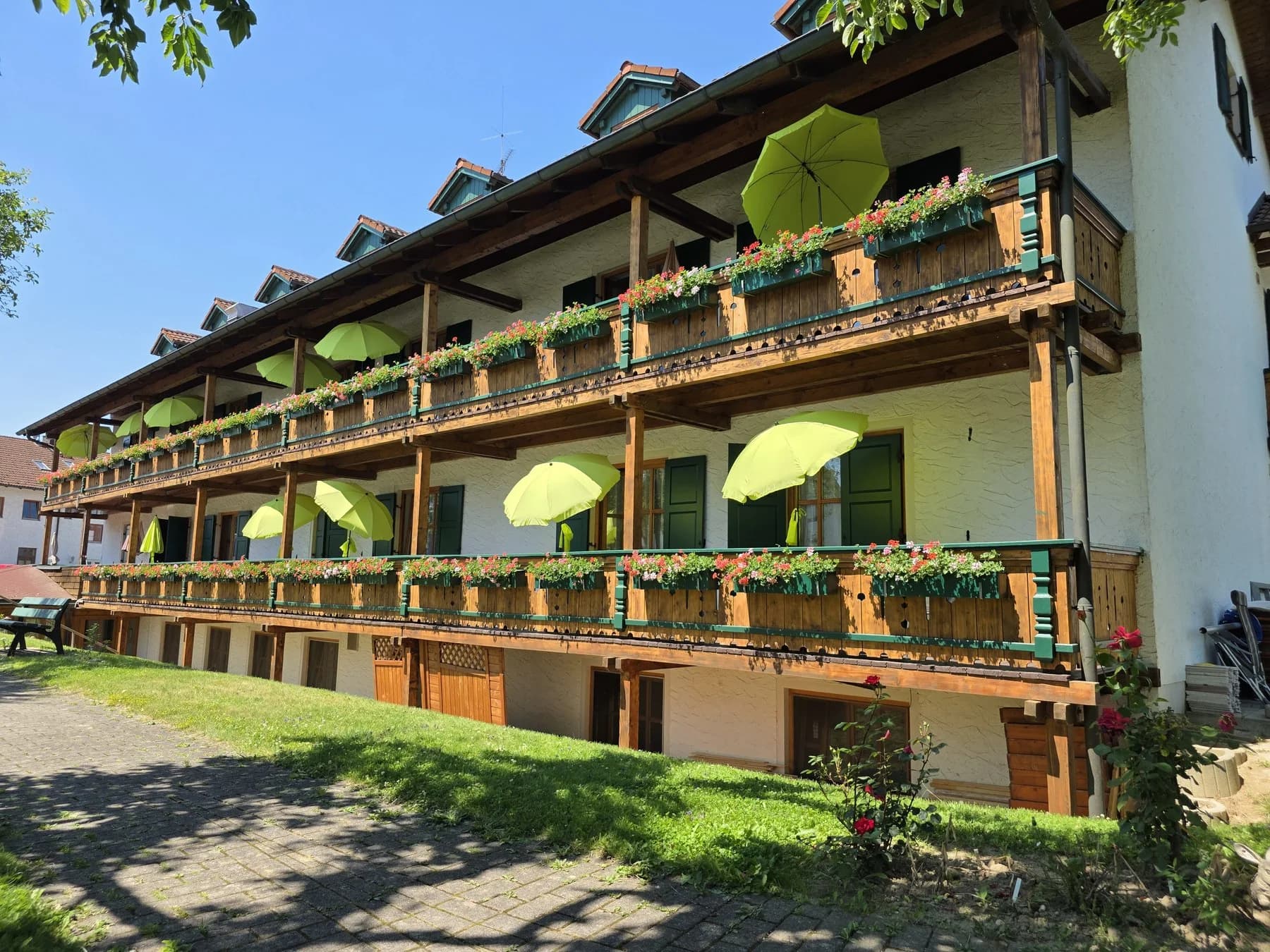 Lange Balkonfront des Pflegeheims mit Garten und Sonnenschirmen